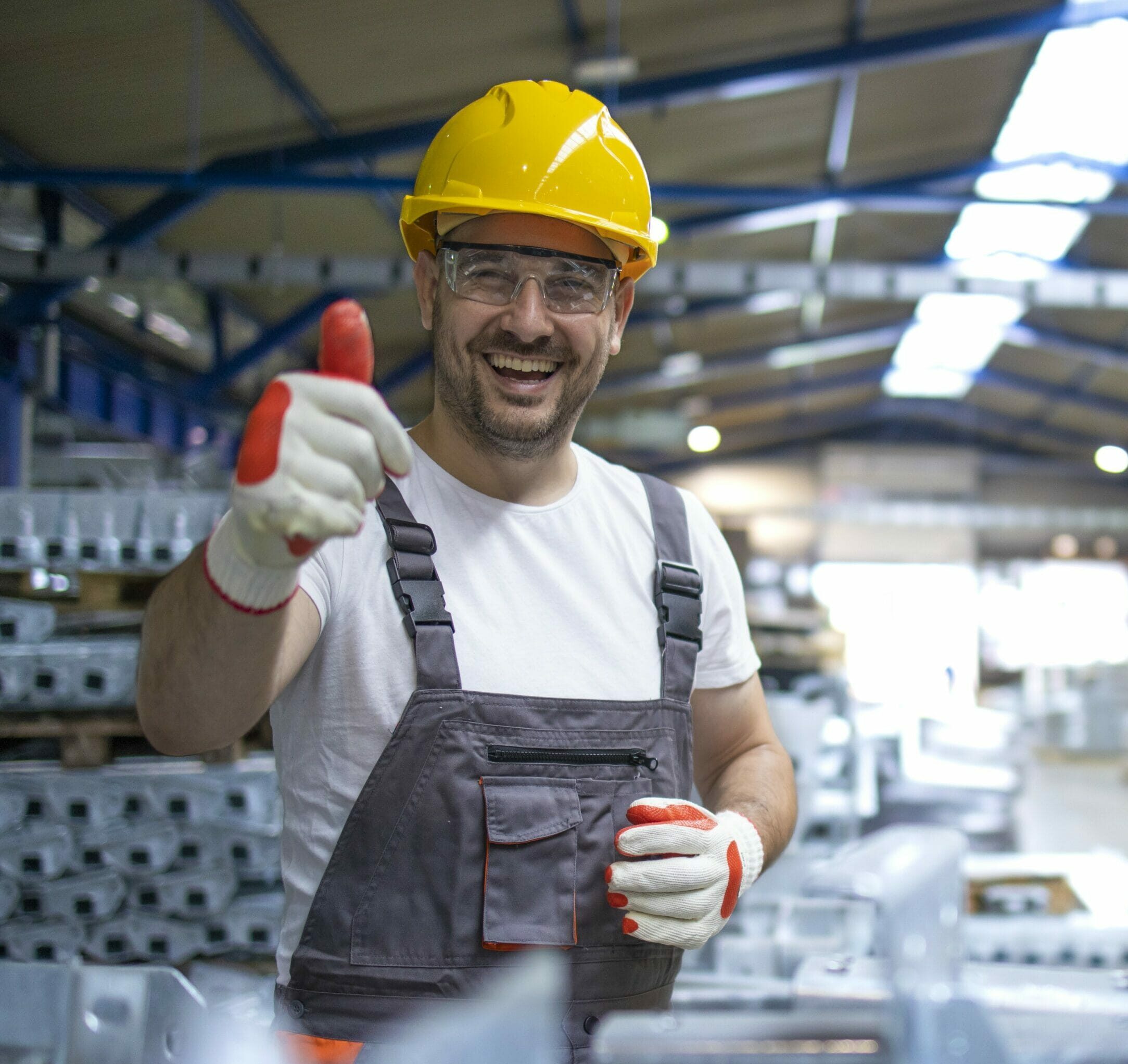 homme dans une usine, avec le pousse levé, qui est heureux